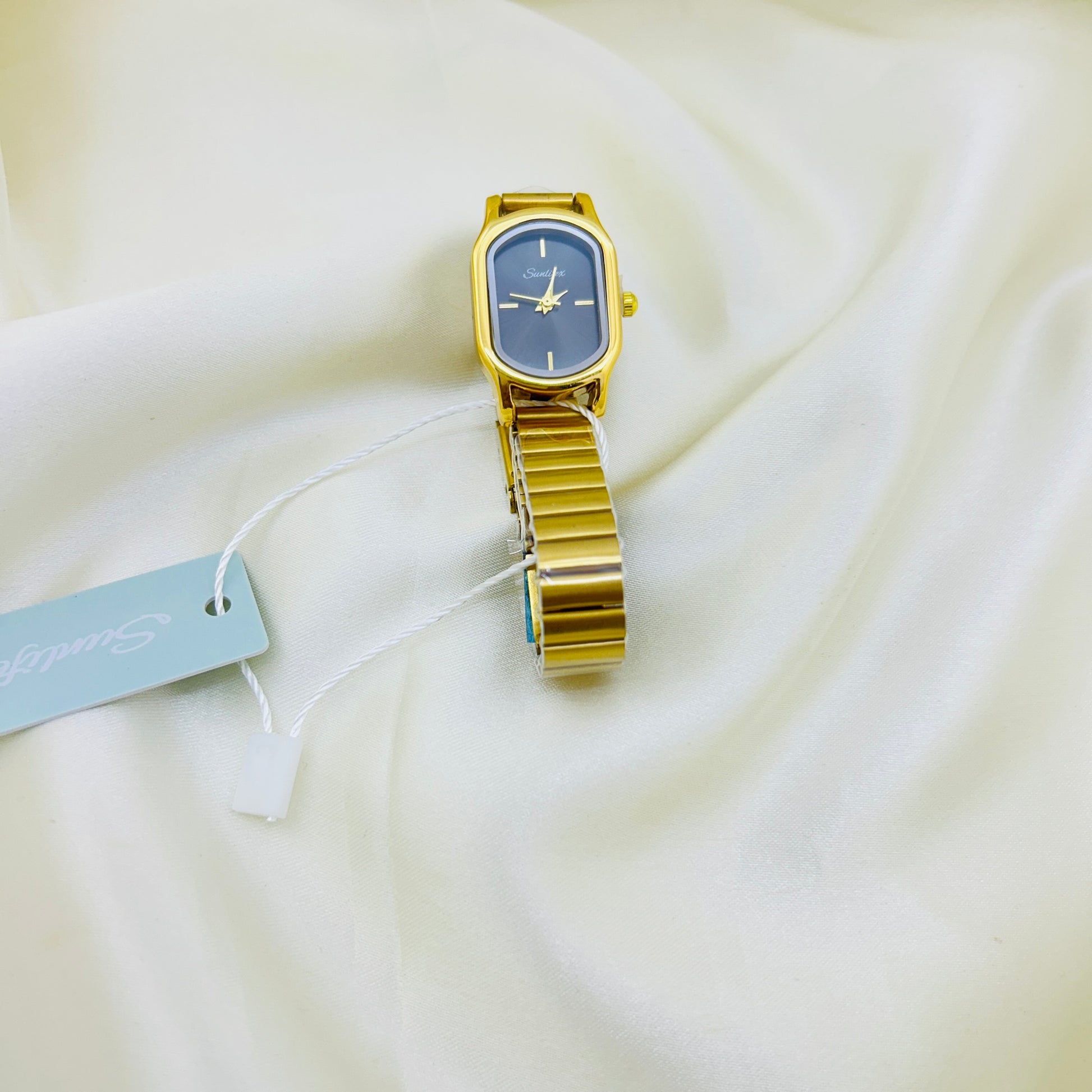 Gold watch with a black face on a white fabric background
