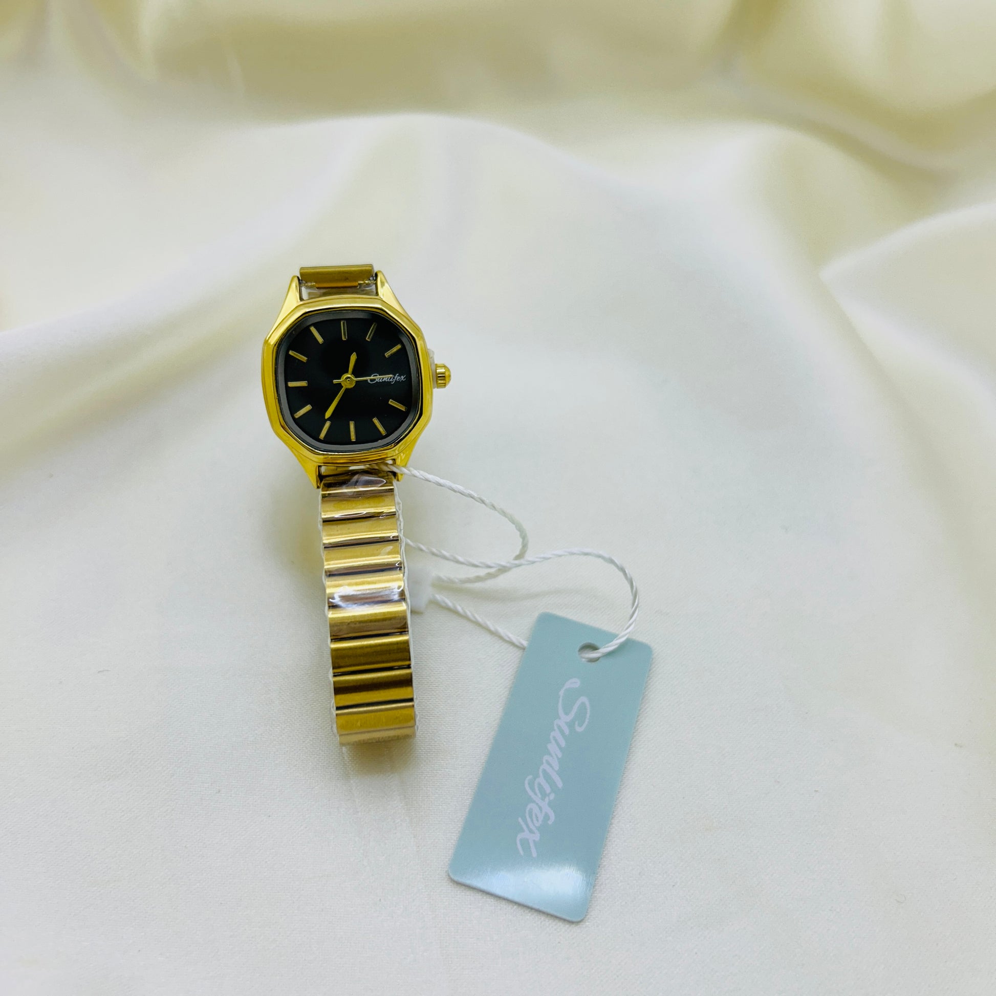 Gold watch with a tag on a white fabric background