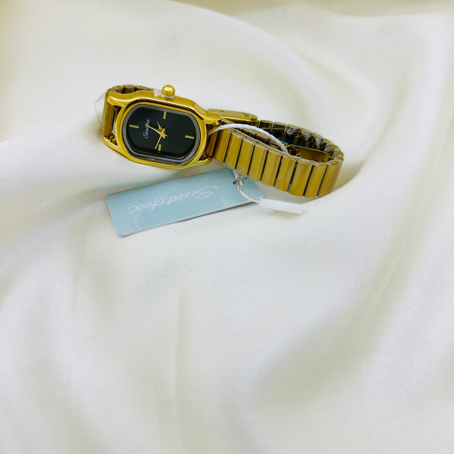 Gold watch with a tag on a white fabric background