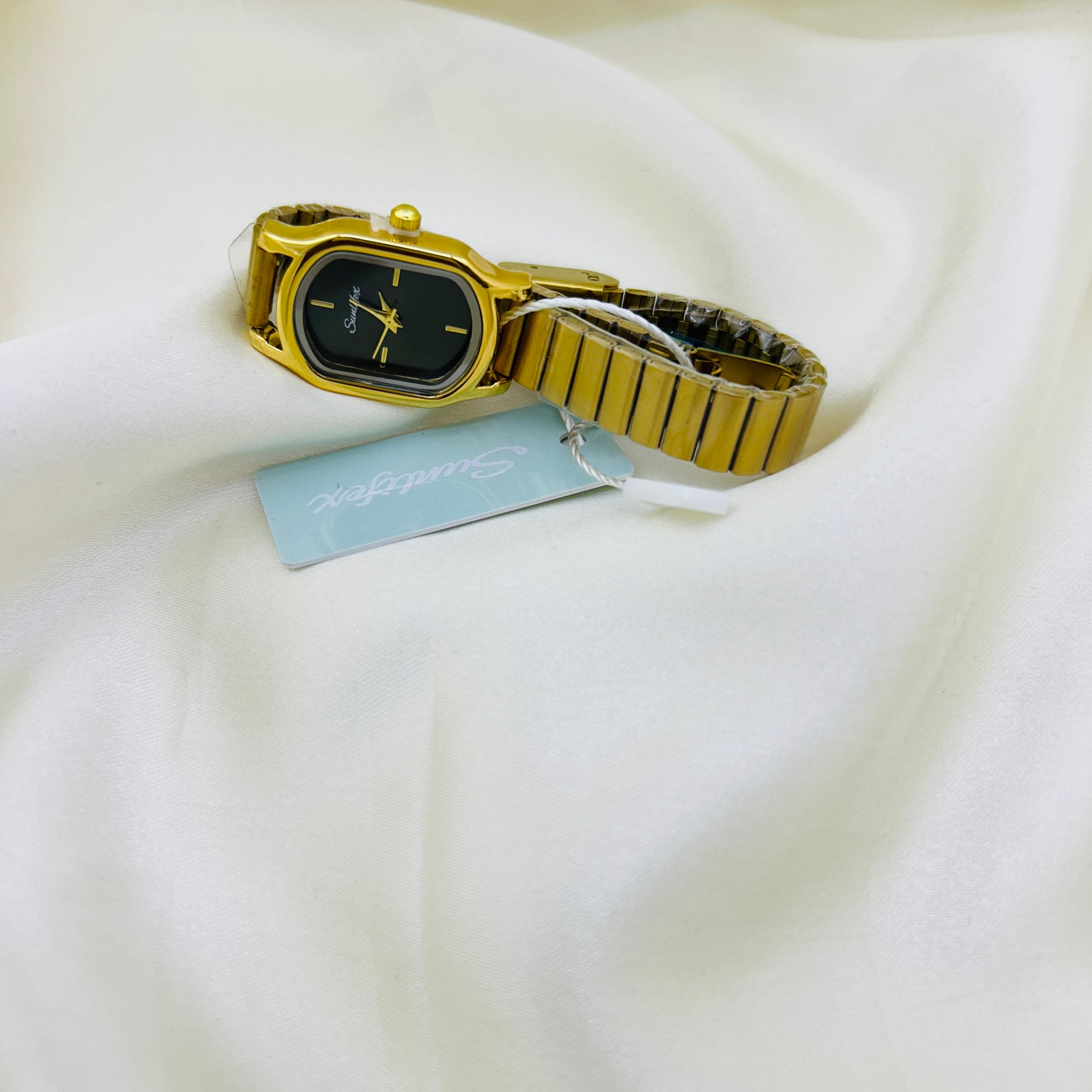 Gold watch with a tag on a white fabric background