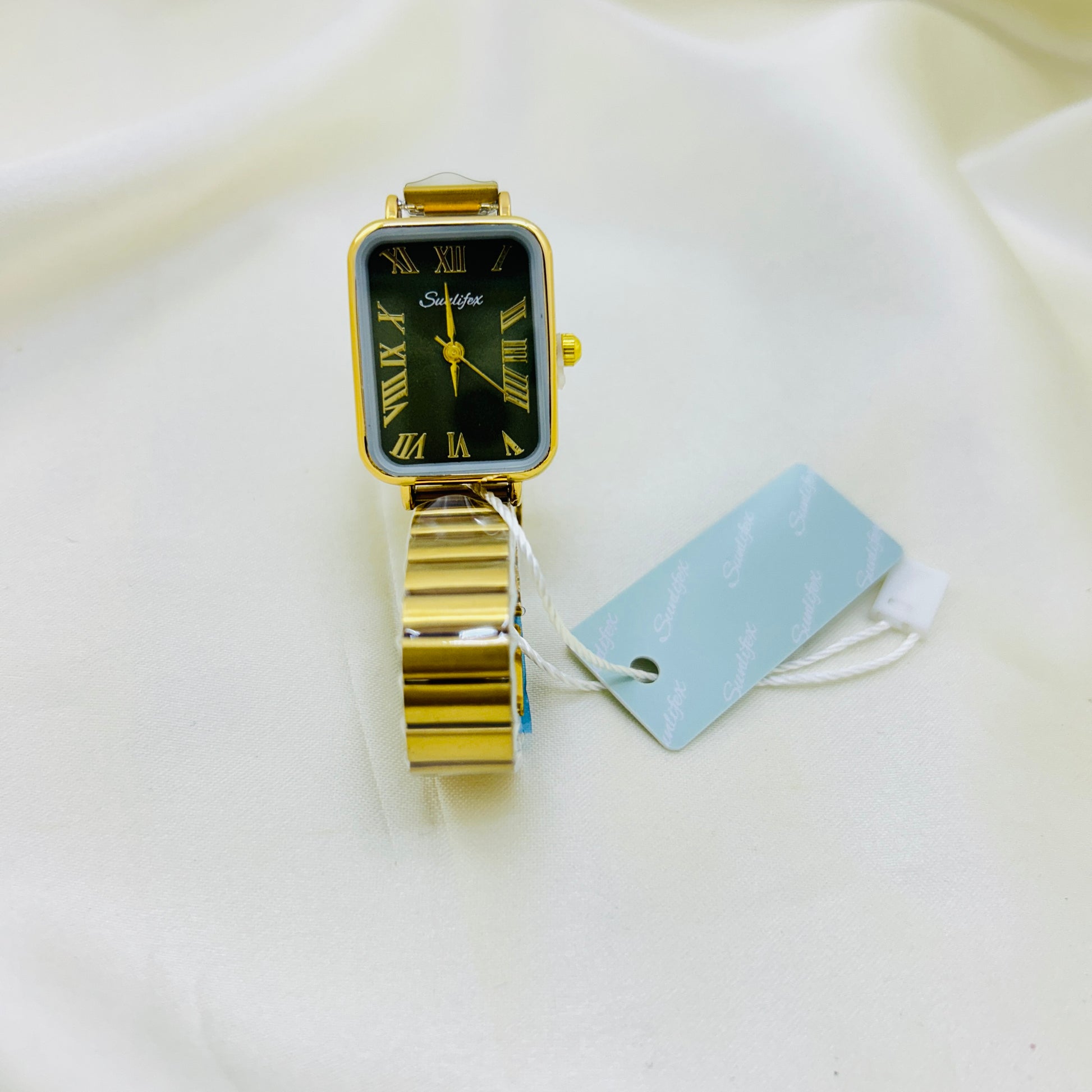 Gold watch with a olive green face on a white surface.