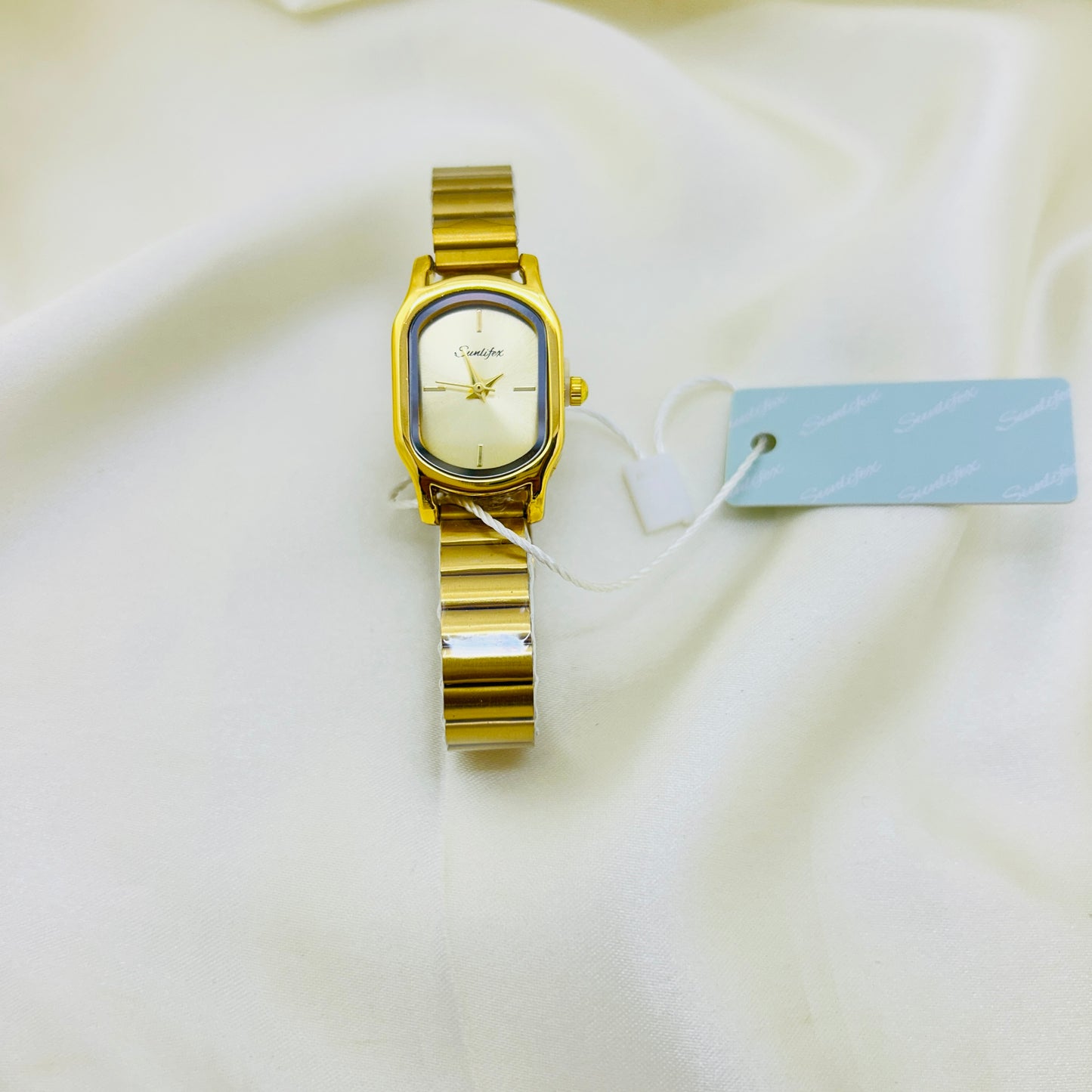 Gold wristwatch with a tag on a white fabric background