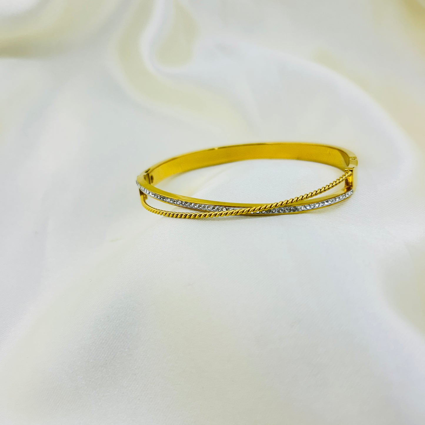 Gold bracelet with small diamonds on a white background