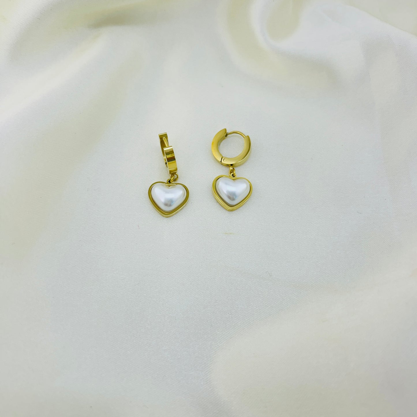 Gold heart-shaped earrings with pearls on a white background