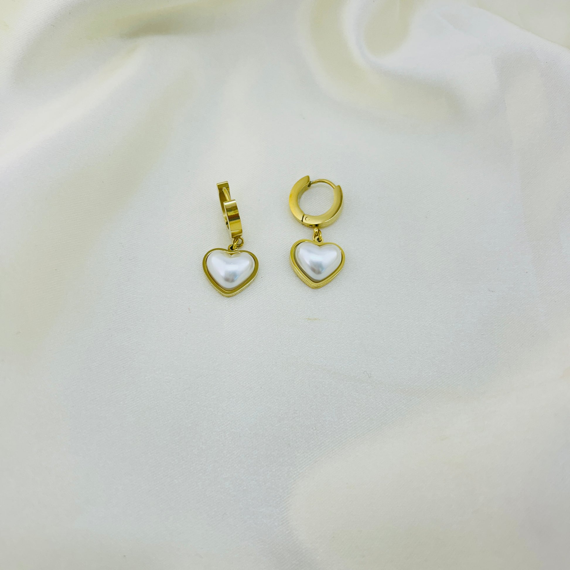 Gold heart-shaped earrings with pearls on a white background