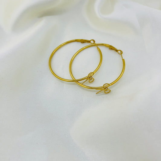 Gold hoop earrings on a white fabric background