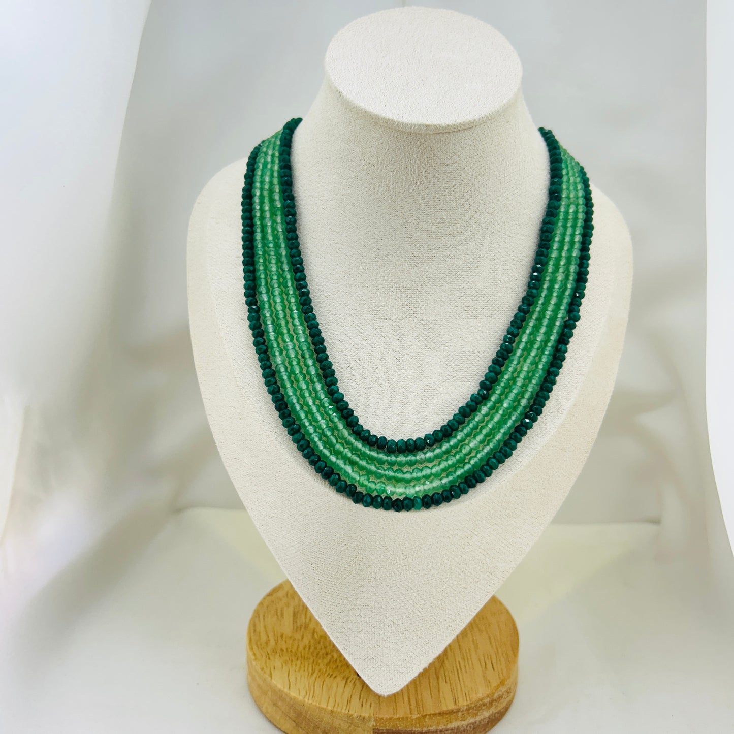 Green beaded necklace on a mannequin bust against a white background