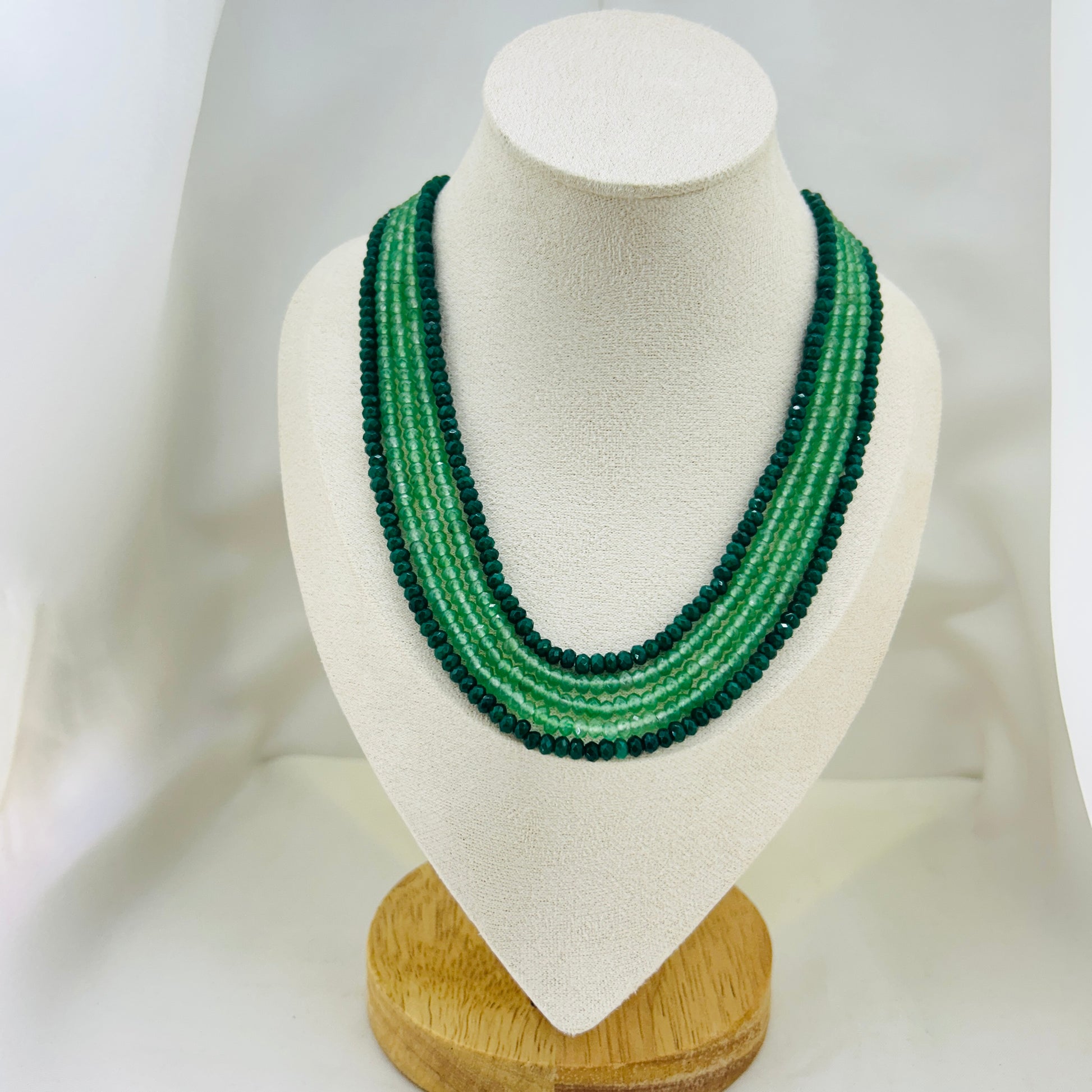 Green beaded necklace on a mannequin bust against a white background