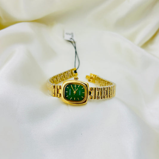 Gold wristwatch with a green face on a white fabric background
