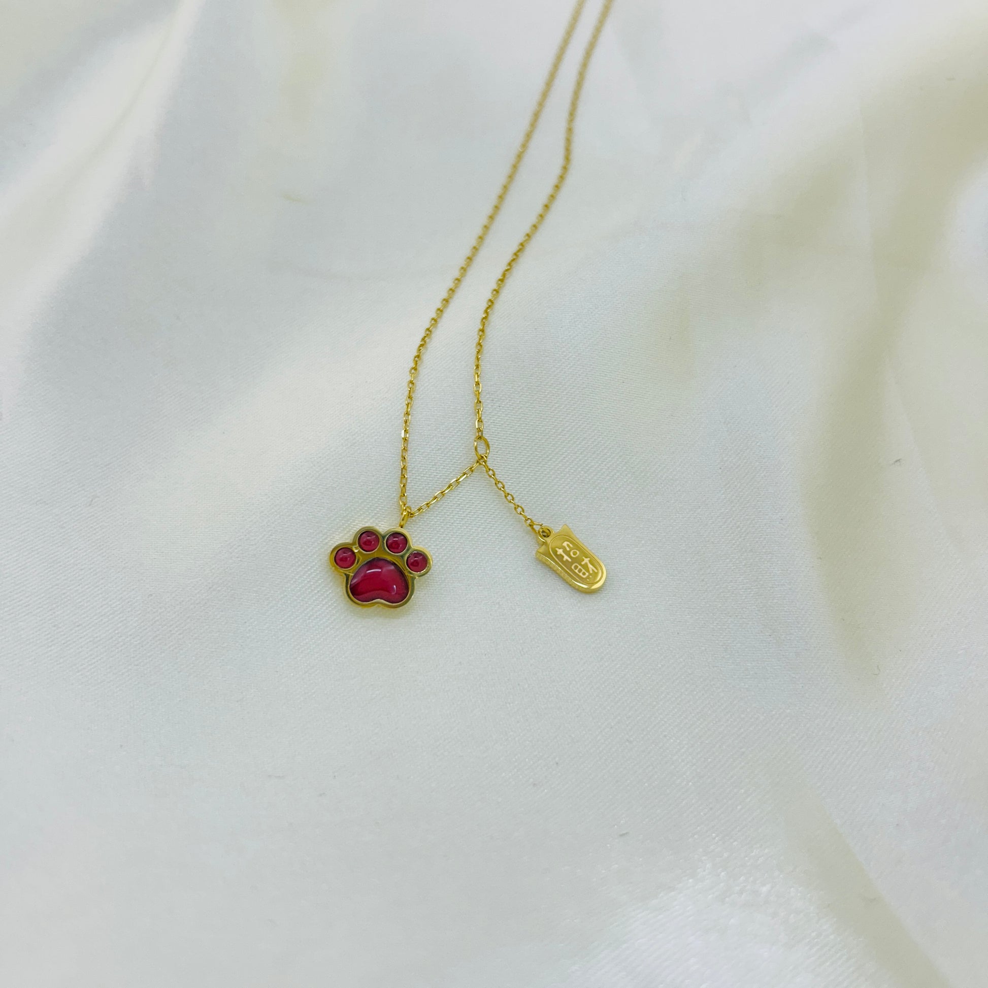 Gold necklace with a paw-shaped pendant on a white background