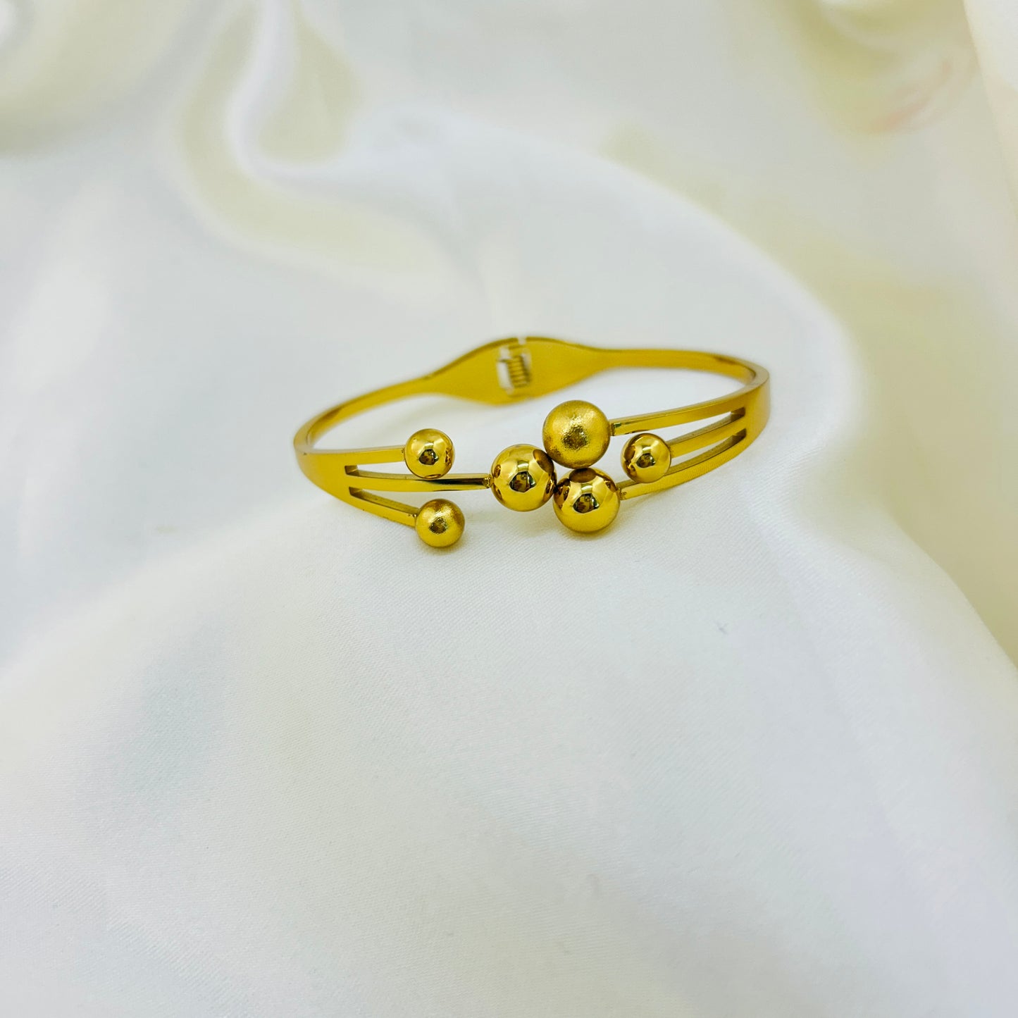 Gold bracelet with spherical beads on a white background