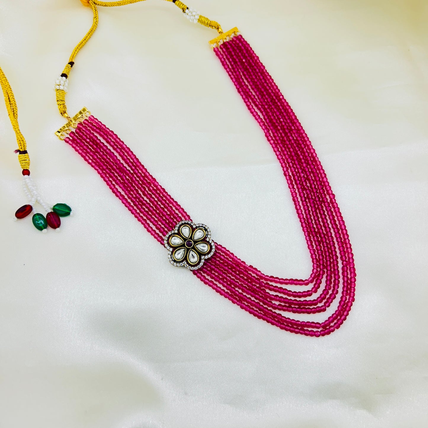 Pink beaded necklace with a decorative clasp on a white background