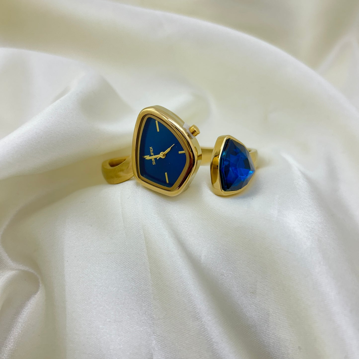 Gold cufflinks with blue stone on a white fabric background