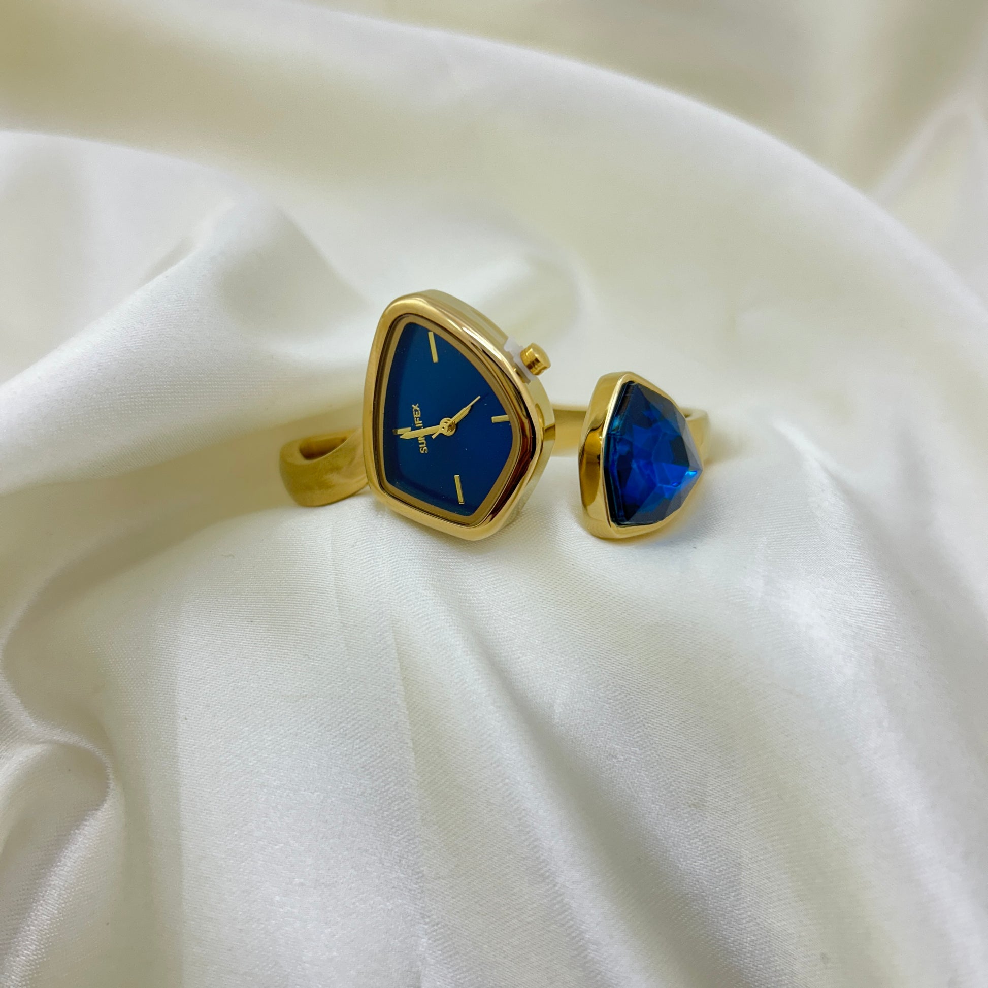 Gold cufflinks with blue stone on a white fabric background