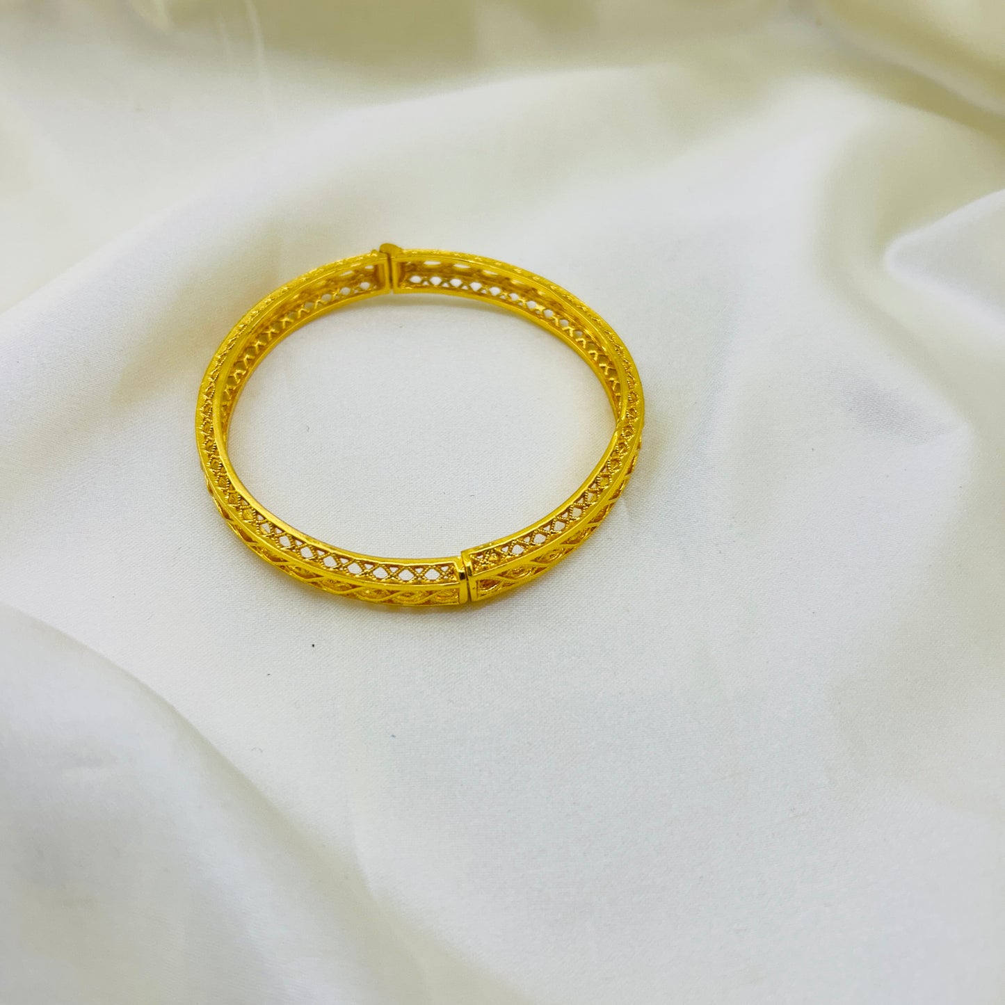 Gold bracelet on a white fabric background