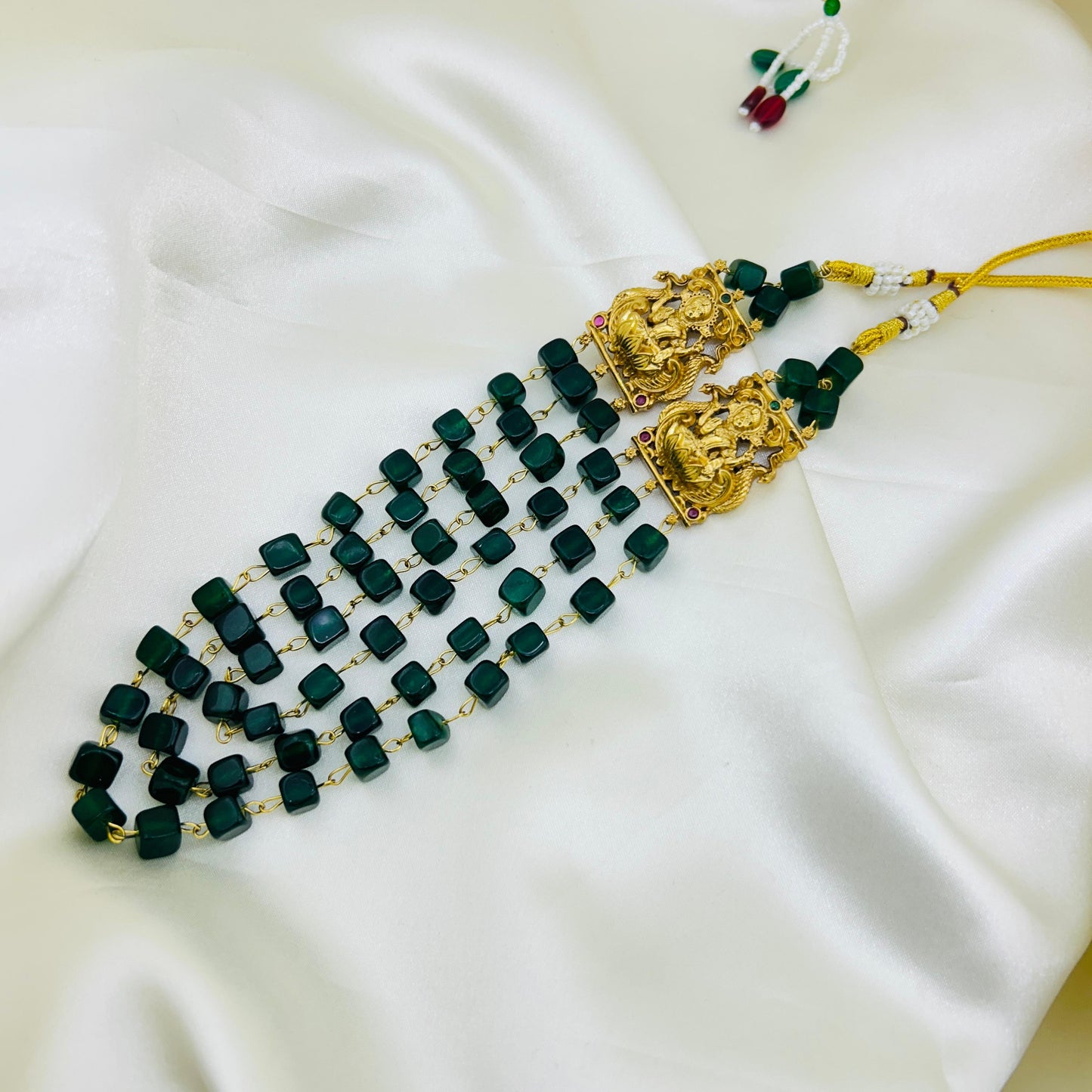 natural Green beaded necklace with gold accents on a white fabric background