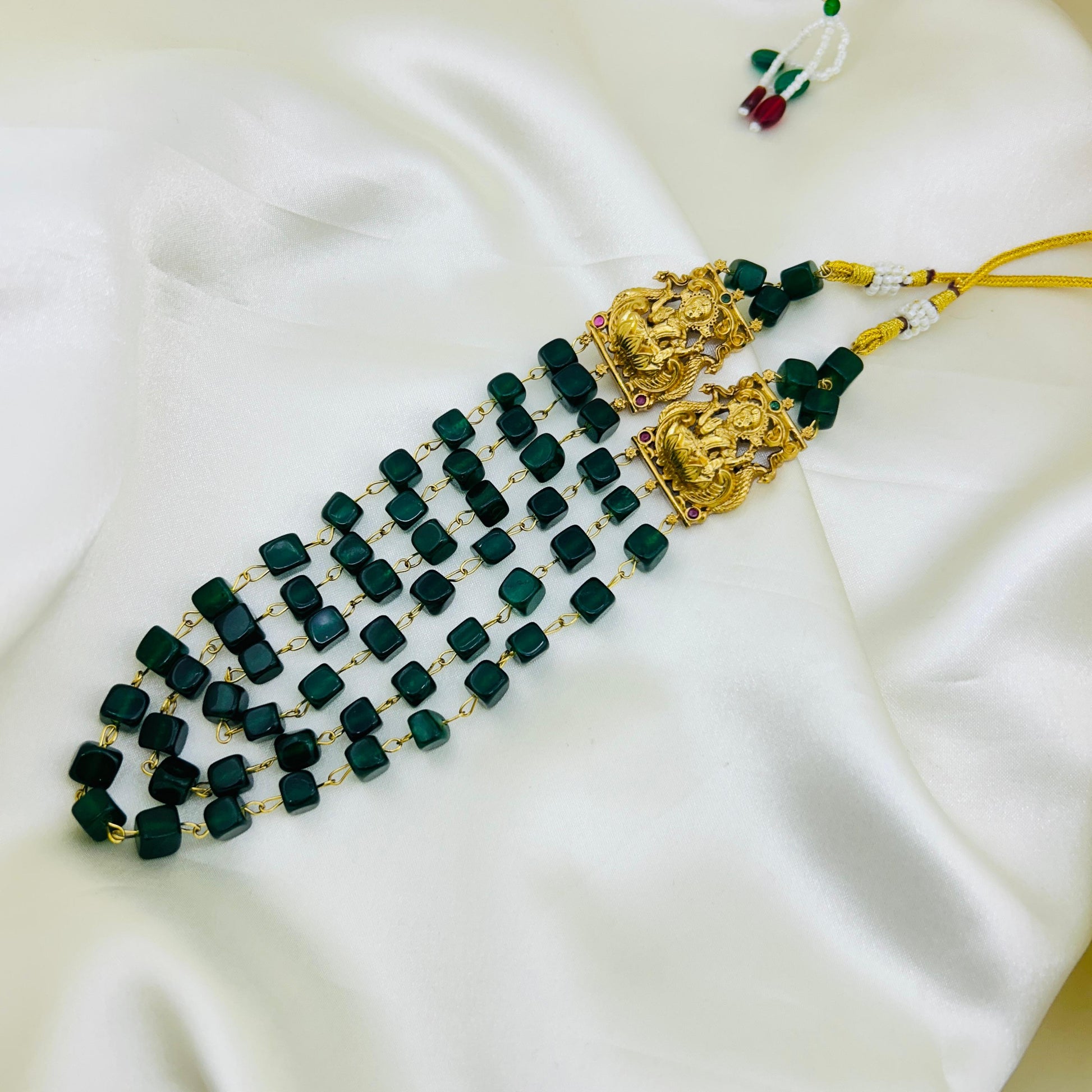 natural Green beaded necklace with gold accents on a white fabric background