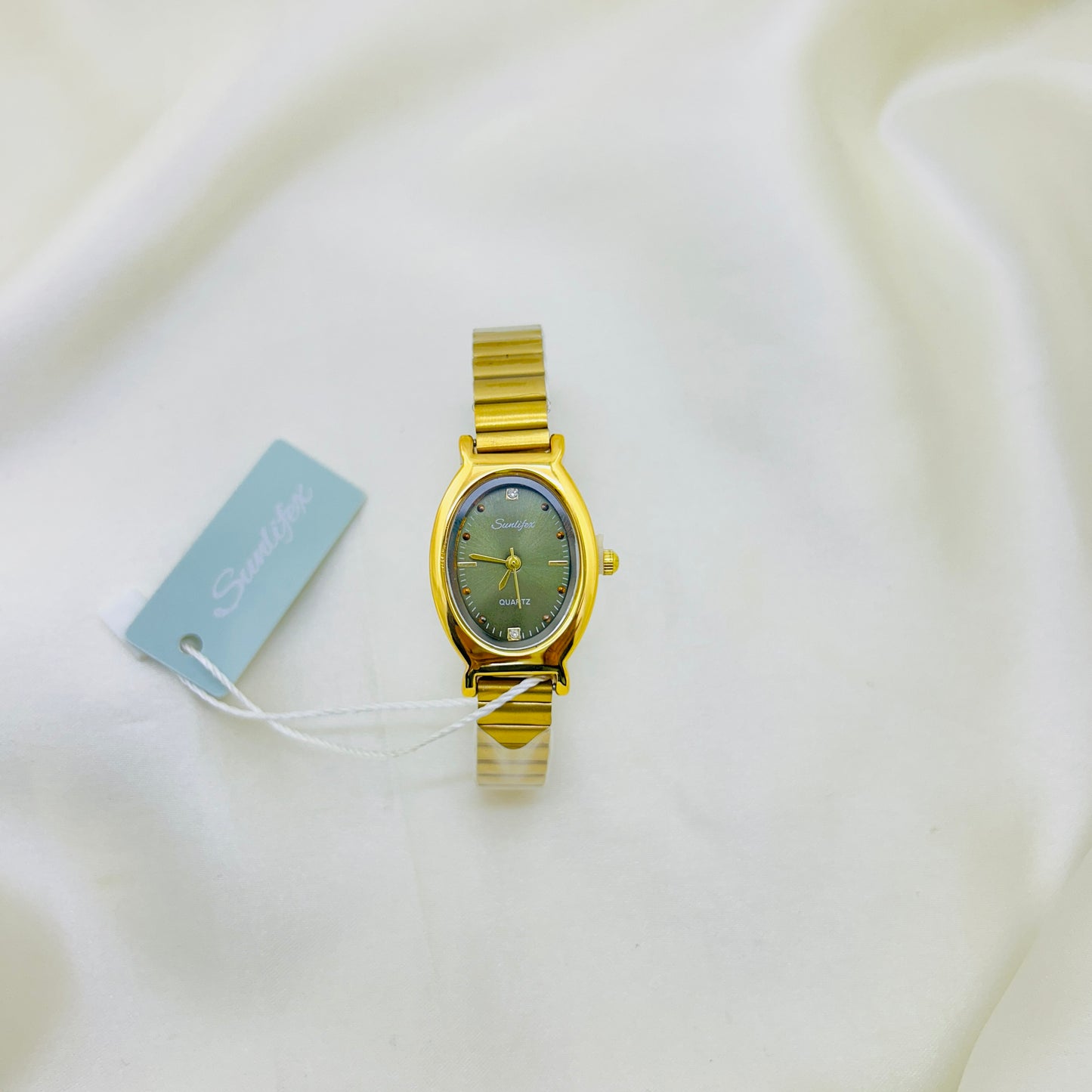 Gold watch with a green face on a white background