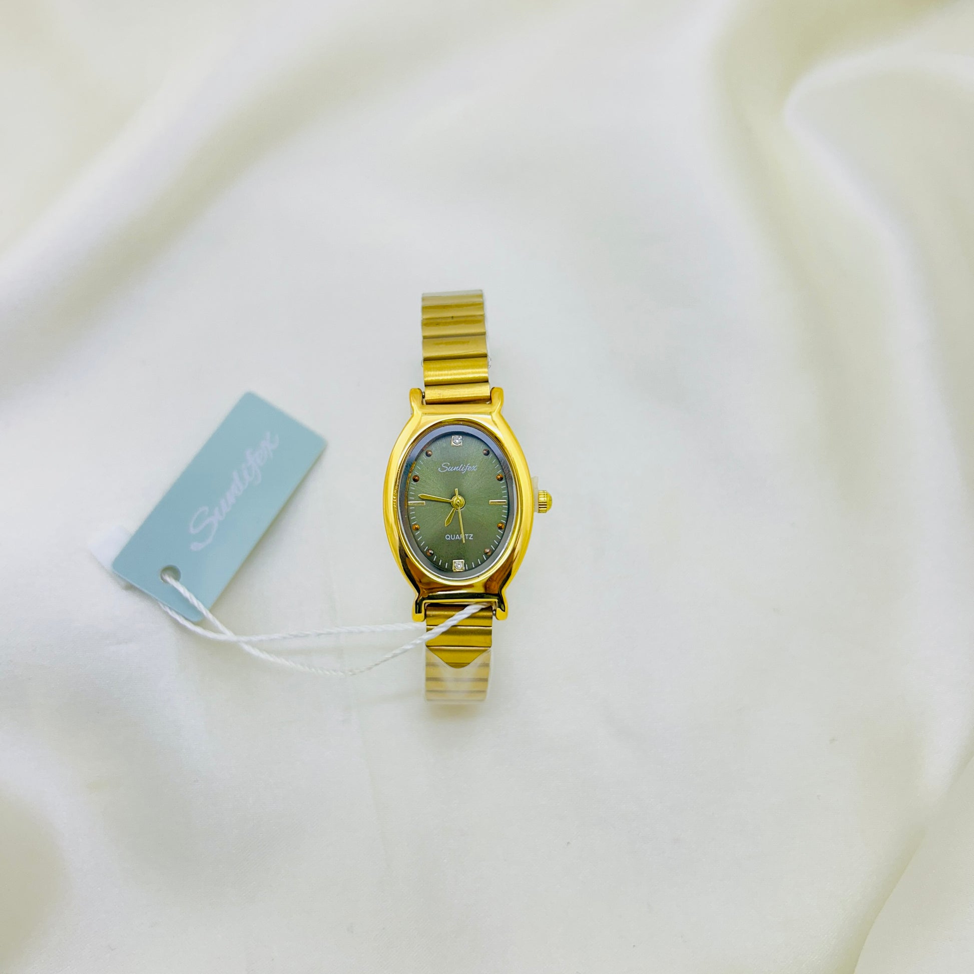 Gold watch with a green face on a white background