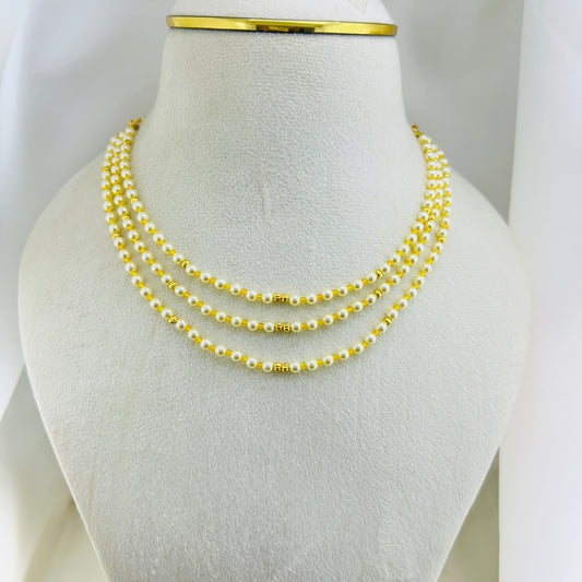 Three-layered swarovski pearl beaded necklace with yellow and gold beads on a mannequin bust.